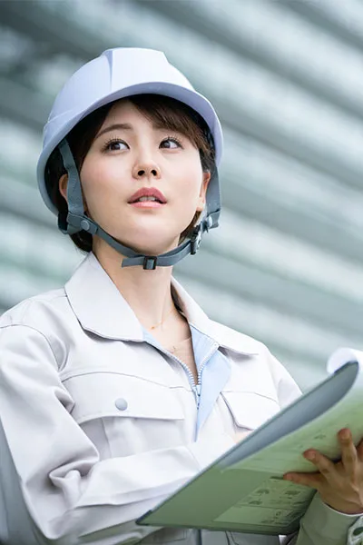 設計図を持ってヘルメットを被っている女性スタッフ